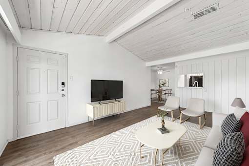 A living room with a white couch, a coffee table, and a television.
