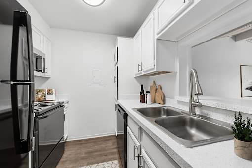 A modern kitchen with a black refrigerator and stainless steel sink.