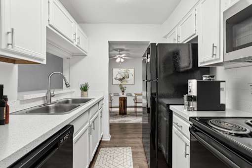 A modern kitchen with black appliances and white cabinets.