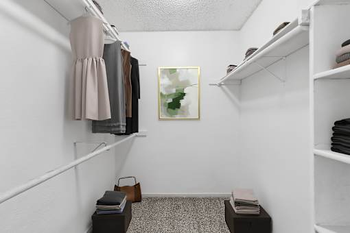 A small closet with a painting on the wall and a shelf with folded clothes.