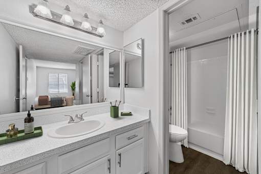 A white bathroom with a sink, mirror, and shower.