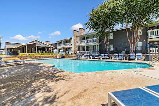 A large swimming pool with a blue tiled edge and a sandy bottom.