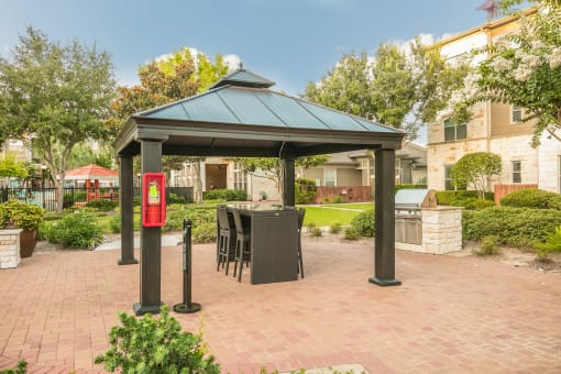 a gazebo with a table and chairs in the middle of a brick patio