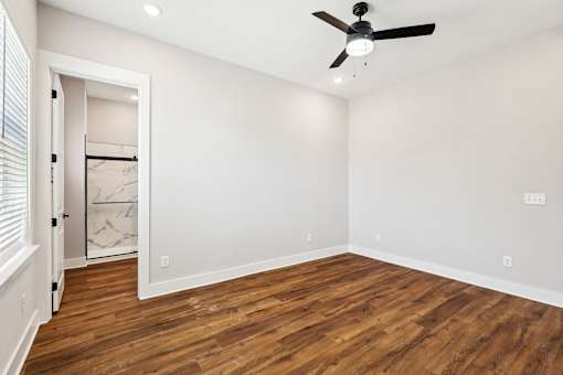 A room with a ceiling fan and wooden flooring.