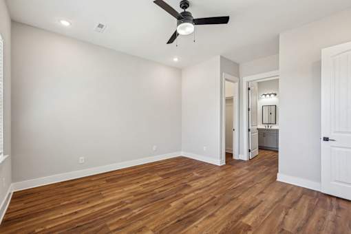 A room with a ceiling fan and wooden floors.
