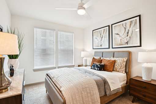 A bedroom with a large bed, a nightstand, and a ceiling fan.