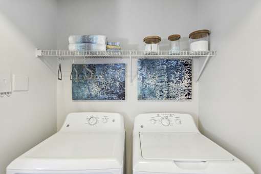 A bathroom with two toilets and a shelf above them.