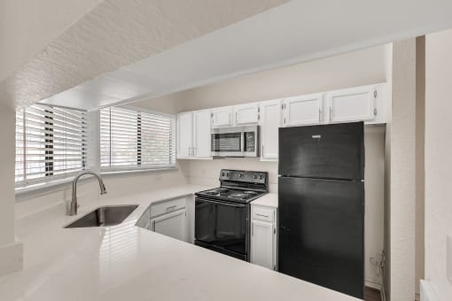 an empty kitchen with black appliances and white cabinets