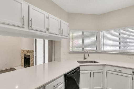 a kitchen with white cabinets and a sink and a window