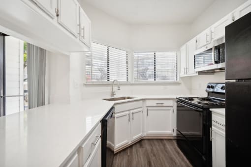a renovated kitchen with white cabinets and black appliances
