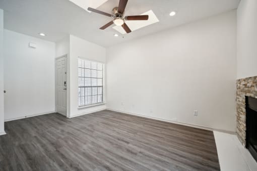 an empty living room with a ceiling fan and a fireplace