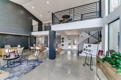 the lobby of a building with a staircase and tables and chairs