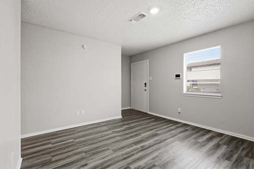 A room with a wooden floor and a window with blinds.
