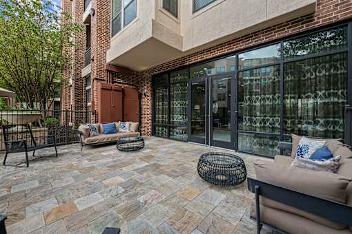 a patio with two couches and chairs in front of a building