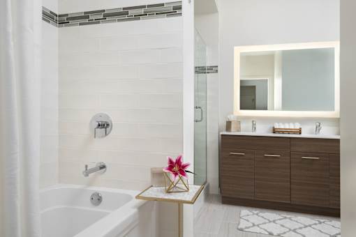 A modern bathroom with a white tub and a wooden vanity.