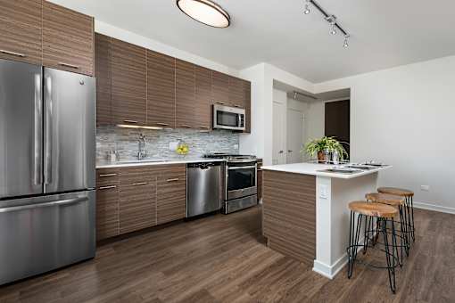A modern kitchen with a refrigerator, oven, and bar stools.