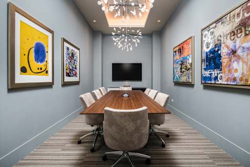 A conference room with a long table surrounded by chairs and framed artwork on the walls.