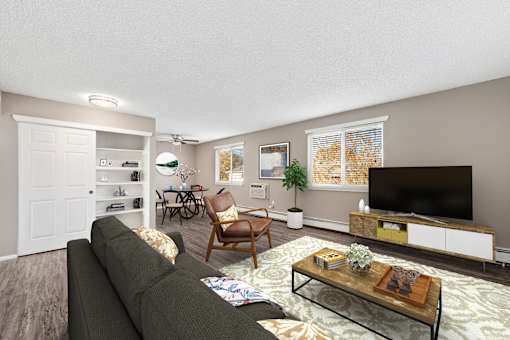 A living room with a grey couch, a wooden chair, a coffee table, and a flat screen TV.