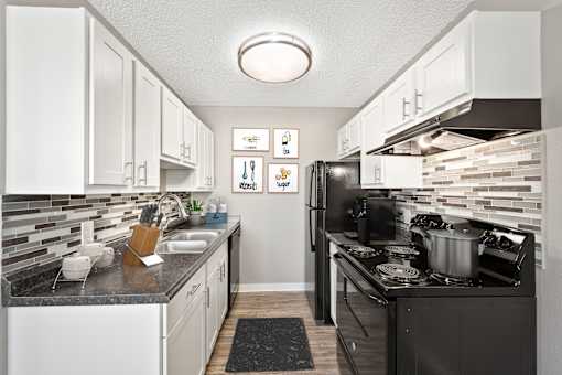A kitchen with black and white appliances and a black counter top.