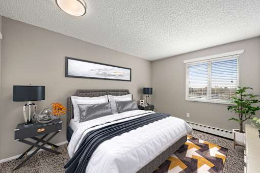A bedroom with a large bed, a nightstand with a lamp, and a framed picture on the wall.
