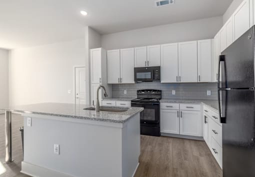 A kitchen with white cabinets and a black refrigerator.