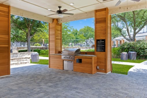 an outdoor kitchen with a grill and a ceiling fan