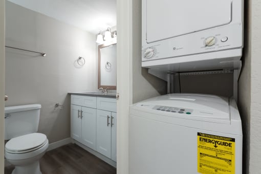 a bathroom with a washer and dryer in it and a toilet and sink