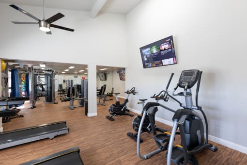 a gym with various exercise equipment and a flat screen tv