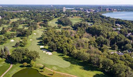 A golf course surrounded by trees and buildings.