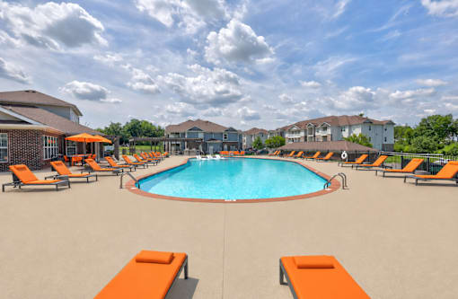 A large swimming pool surrounded by orange lounge chairs.