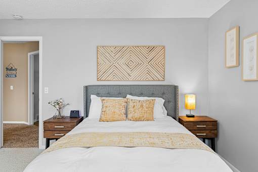 A bedroom with a large bed and a grey headboard.