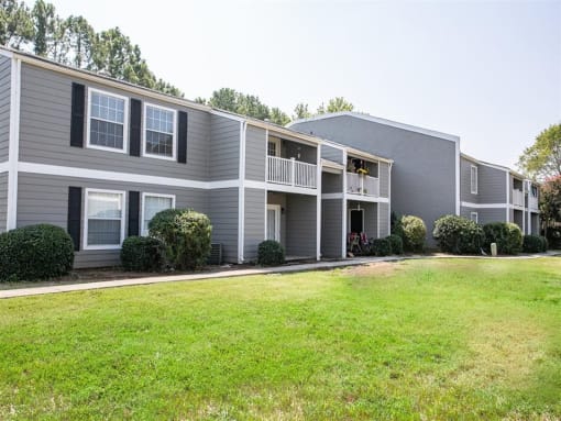 a gray apartment building with a grassy yard