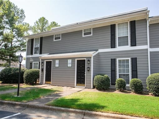 a gray house with black shutters and a lawn
