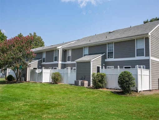 a gray house with a yard and a white fence