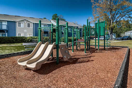A playground with a green swing set and a slide.