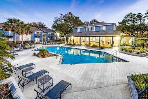 A swimming pool surrounded by a concrete patio and lounge chairs.