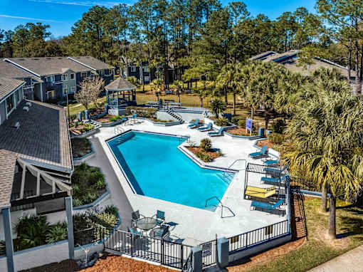 A swimming pool surrounded by a fence and chairs.