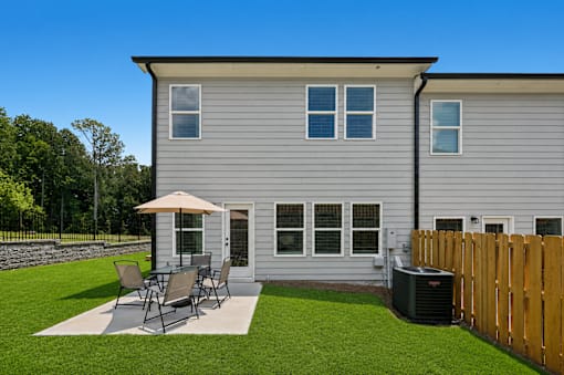 A grey house with a patio and a wooden fence.