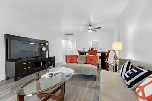 A modern living room with a glass coffee table and a television.