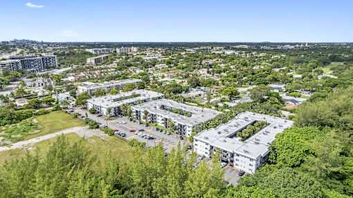A bird's eye view of a residential area with multiple buildings and greenery.