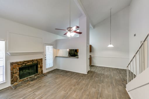an empty living room with a fireplace and a ceiling fan