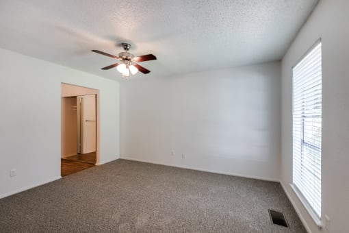 the living room of an empty house with a ceiling fan