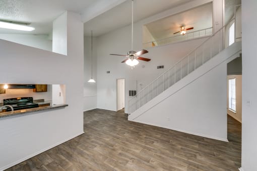 the living room and entryway of a house with white walls and a ceiling fan