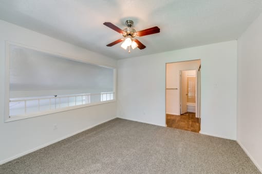 an empty living room with a ceiling fan