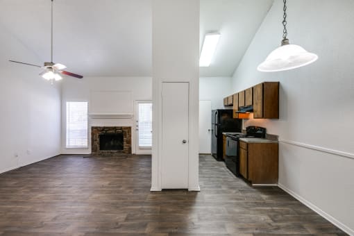 an empty living room with a fireplace and a kitchen