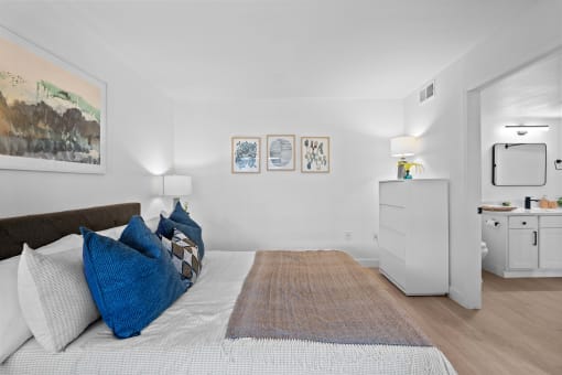 a bedroom with a bed with blue pillows and a rug