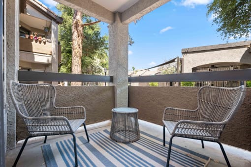 a patio with two chairs and a table on a balcony