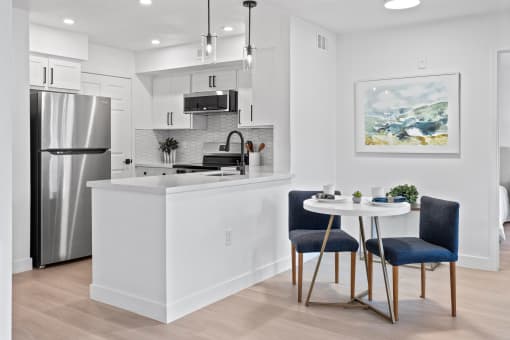 an open kitchen and dining area with a table and chairs and a refrigerator