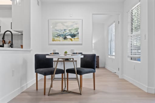 a dining room with a white table and two black chairs