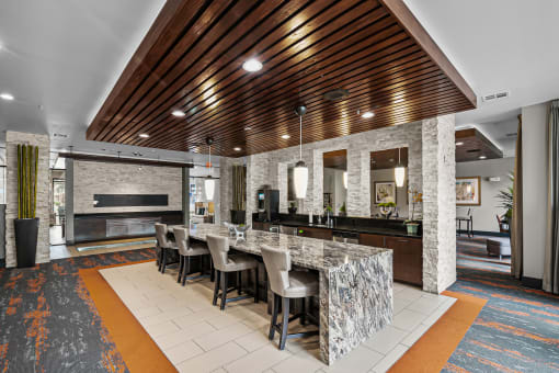 a large kitchen with a marble counter top and a long table with chairs
